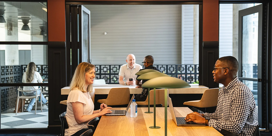 People with laptops talking at table